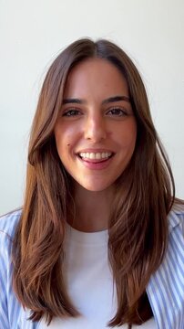 A friendly young woman with long brown hair smiles, talks, and expresses a range of emotions against a white background, conveying happiness, sincerity, and authentic communication.
