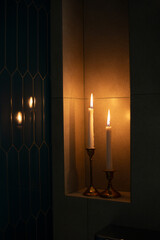 Two burning wax candles in a modern bathroom niche. © Olena