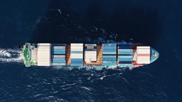 Shipping logistics. Commercial shipping. Cargo ship at sea, aerial top view. Freight container loaded on cargo tanker. Aerial cargo ship passing harbor. Cargo business. Container ship