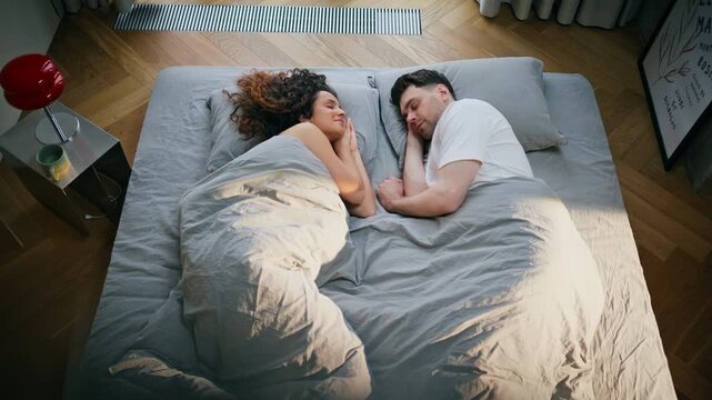 Man and woman sleeping together bed morning. Pair resting cozy bedroom top view.