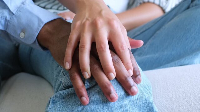 A tender close-up of a diverse couple's hands intertwining, symbolizing love, connection, and intimacy. Their fingers gently interlock, creating a powerful image of unity, care, and partnership, perfe