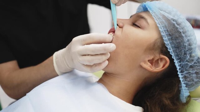 Pediatric dentist carefully extracting a primary tooth from a young patient in a dental office. Concept children's dentistry, dental treatment, oral health, professional dental care, pediatric medicin