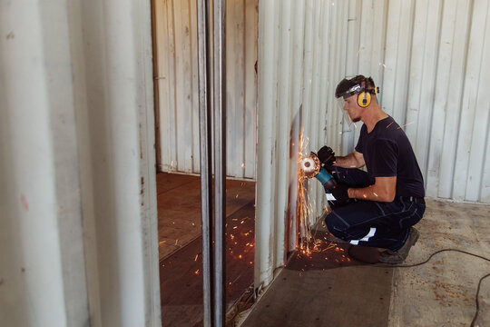 Young man cutting a shipping container with circular saw