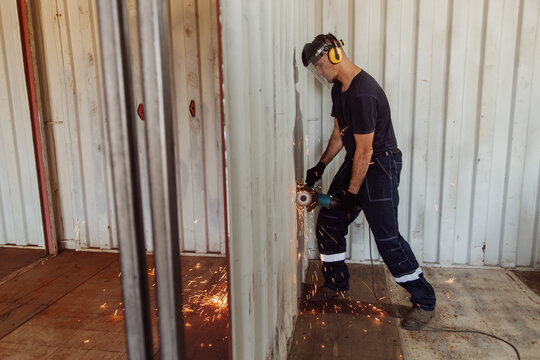 Young man using circular saw on shipping container