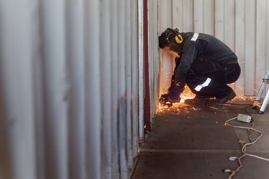 Man cutting shipping container with circular saw
