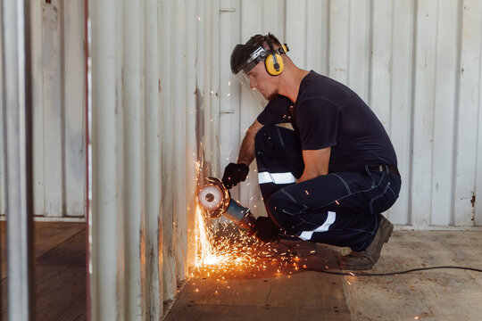 Young man cutting shipping container with circular saw