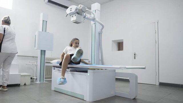 Radiologic technologist preparing a teenage girl for an X-ray examination in a modern medical clinic. Concept diagnostic imaging, radiology, medical examination, healthcare, preventive medicine.