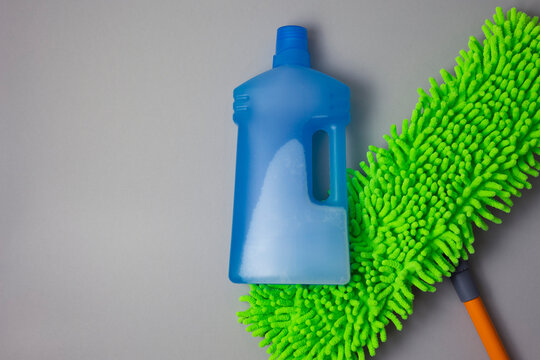 Floor cleaner bottle and microfiber mop on color background
