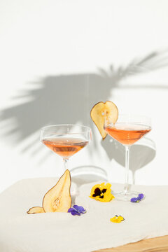 Two rose wine glasses with summer cocktails and dried fruit appetizers