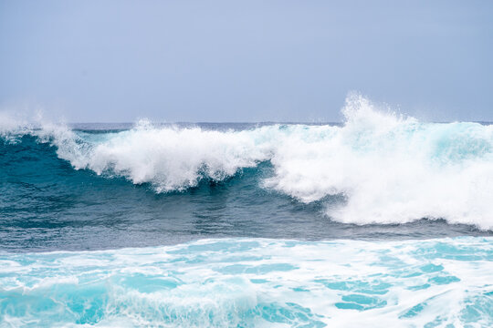 Powerful blue ocean waves crashing with white foam