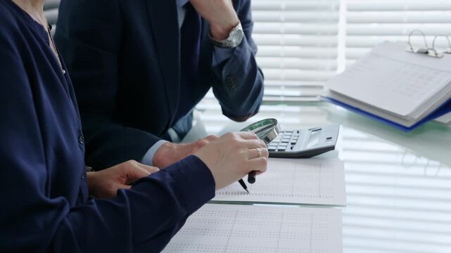 Professional auditors and accountants reviewing financial documents, discussing data, calculating taxes and expenses during an important business audit meeting