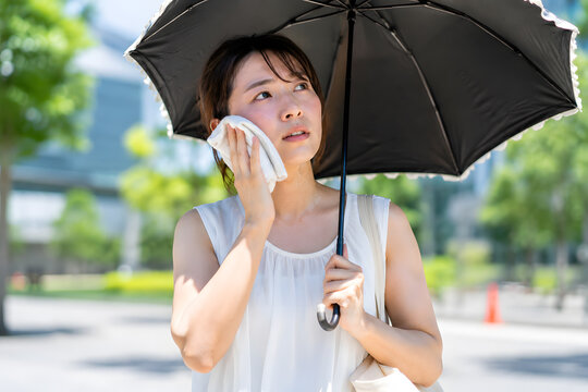 真夏の日傘で暑さ対策をする日本人女性
