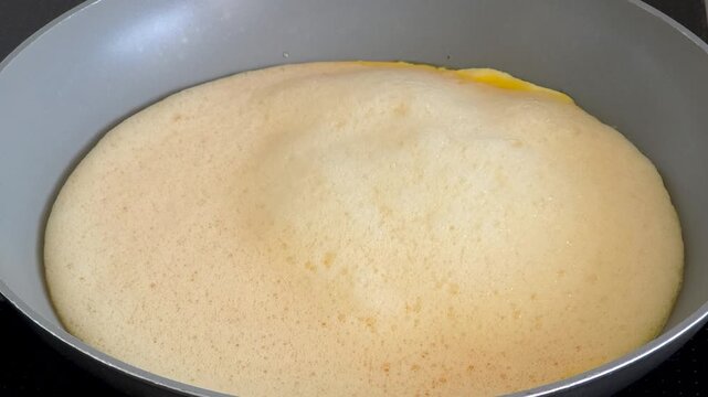 Cooking timelapse of a homemade omelet with melted cheese in a frying pan, preparing breakfast with organic farm eggs, close up food video.