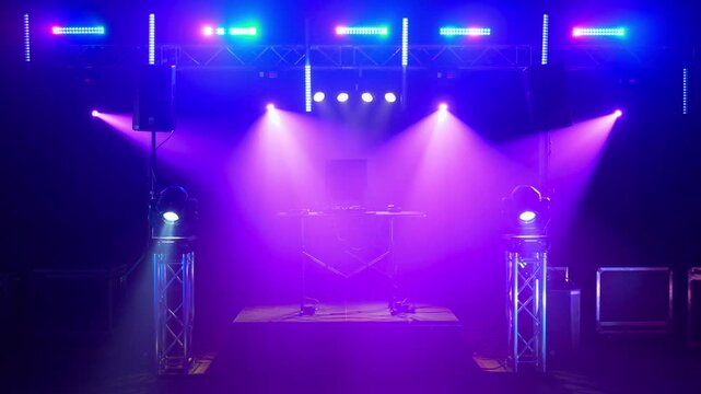 Colorful stage lighting setup with DJ equipment and truss rigging
