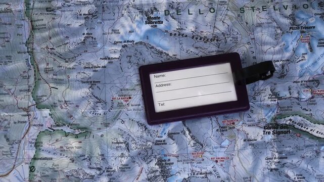 Concept to packing for a holiday in the Alps: Luggage tag placed on a detailed topographic map of Stelvio National Park in Italy