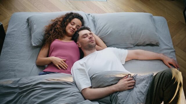 Couple napping together bed top view. Young pair resting cozy weekend home.