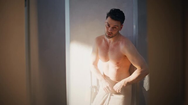 Attractive man drying off with towel. Fresh male after shower morning routine
