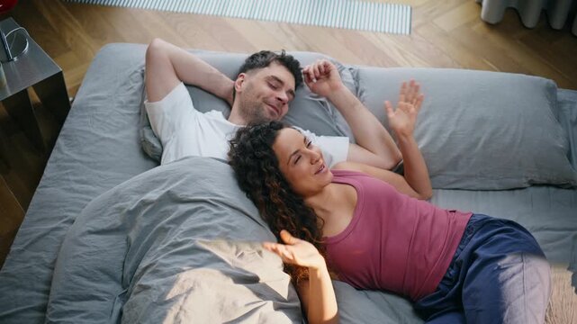 Couple relaxing bed talking laughing morning. Man woman resting bedroom weekend.