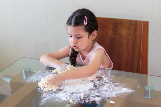 Ni&ntilde;a amasando masa con las manos para preparar pasta