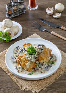 Chicken thighs with creamy mushroom and cheese sauce on a wooden table.