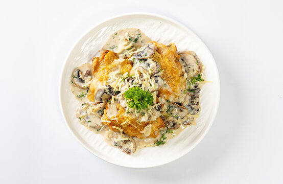 Chicken thighs with creamy mushroom and cheese sauce on a white background.
