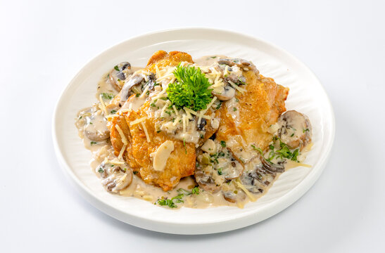 Chicken thighs with creamy mushroom and cheese sauce on a white background.