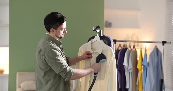 Man steaming shirt with modern steamer at home