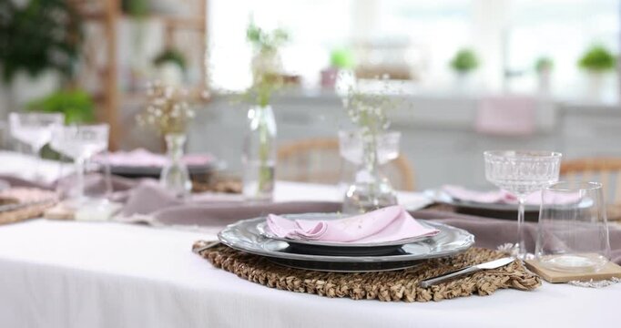 Beautiful place setting with floral decor on table in dining room, closeup. Camera moving