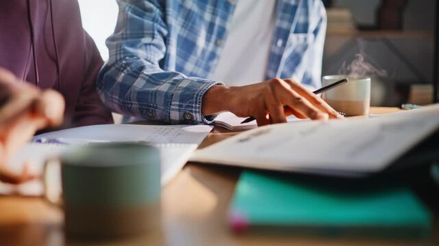 Closeup couple sketching ideas, writing notes at home desk. Students brainstorm