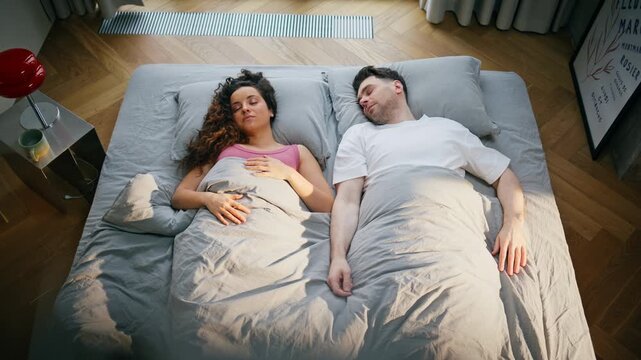 Young couple sleeping bed sunny morning. Man woman resting weekend home bedroom.