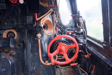 Interior view of vintage steam locomotive cabin with red valves and levers and pipes © Holger