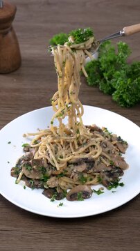 Spaghetti with champignon mushrooms and cream cheese on a wooden table