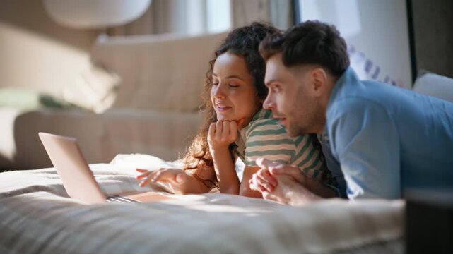 Couple relaxing bed with laptop. Man woman browsing internet cozy home weekend.