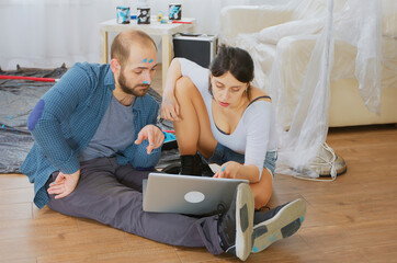 Obraz premium Couple during home renovation using laptop, apartment redecoration and home construction while renovating and improving, repair and decorating.