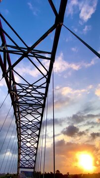 Low angle shot of a steel truss bridge structure against blue sky with white clouds