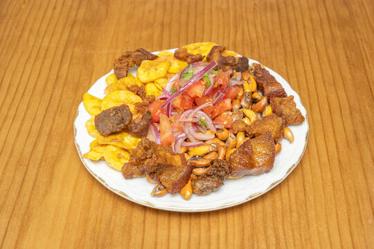 Ecuadorian sharing platter with fried pork chicharr&oacute;n, toasted corn, plantain chips, and fresh tomato-onion salsa on a plate.