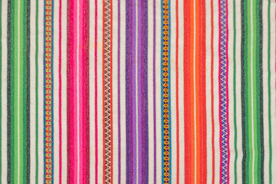 Close-up of a traditional Peruvian striped textile with vibrant multicolor patterns woven into fabric.