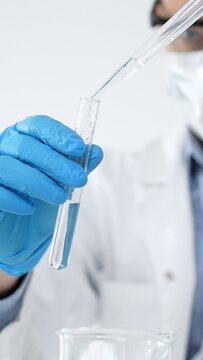 Scientist in blue glove carefully adding liquid from a pipette into a test tube, performing a crucial laboratory experiment for medical research and development