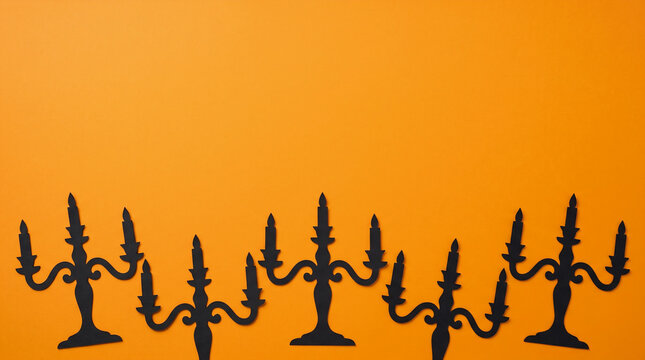 Halloween orange background featuring black candelabra paper cut out bottom border, spooky copy space for gothic party invitation, greeting card, banner, poster and autumn design
