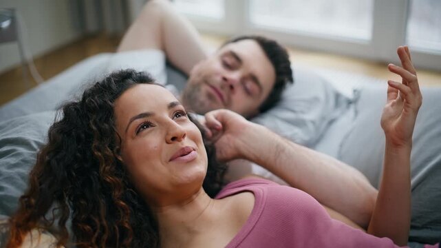 Loving couple relaxing bed together. Closeup laughing woman beside boyfriend.