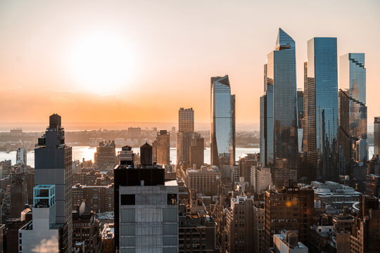 View of mid-town Hudson Yards from an aerial perspective during sunset with the Hudson River behind.
