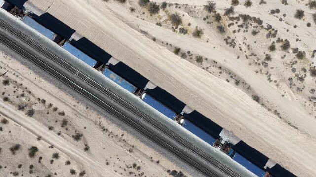 Direct overhead aerial view of a cargo freight train traveling through a California desert landscape