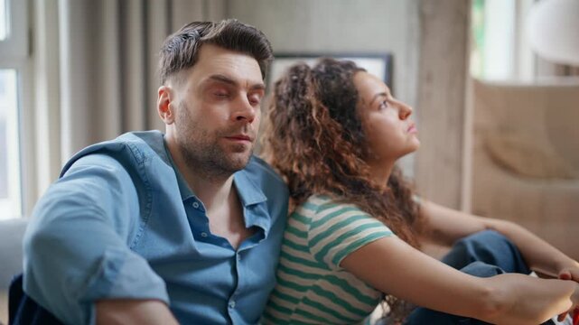 Upset couple sitting back to back after quarrel. Close up sad man thinking home.