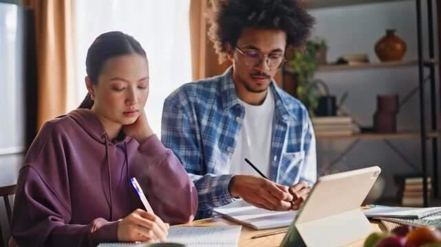 Multiethnic students doing homework closeup. Diverse pair studying together.