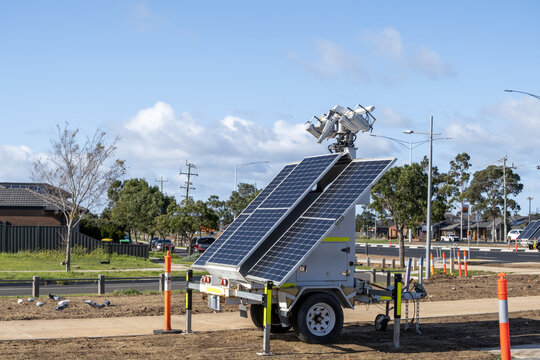 A mobile solar-powered light tower stands on a trailer at a road construction site on roadside in Melbourne Australia. Temporary renewable-energy infrastructure supporting road works