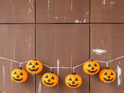 Cute halloween pumpkin face string lights hanging on a rustic brown wooden wall background