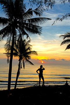 Sunrise with silhouette woman and coconut