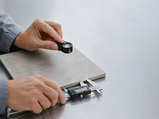 Fototapeta premium Quality Inspector Examining a Ceramic Tile with Caliper and Loupe, Manufacturing Precision Background with Copy Space