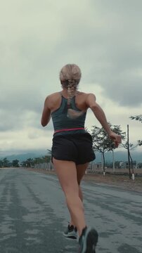 Back view of braided female runner on a tree lined road