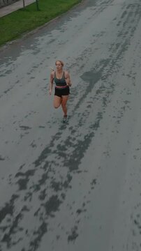 Elevated front view of female runner approaching along a road